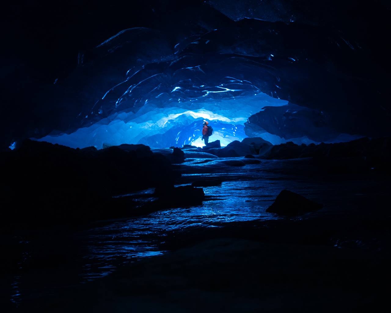 guide lit up inside dark ice cave